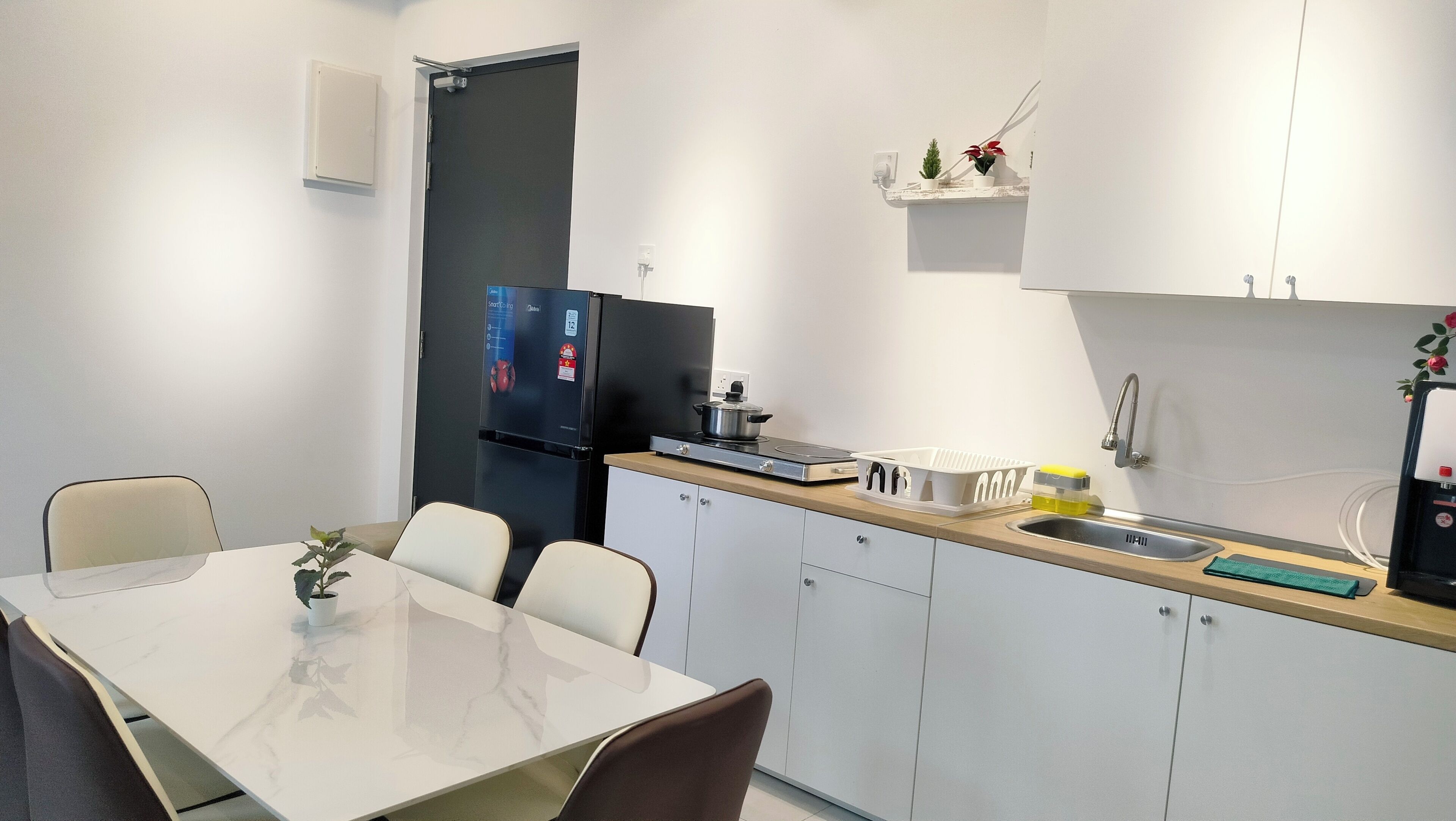 Eine kleine Küche mit Kühlschrank, Herd, Spüle und weißen Schränken.