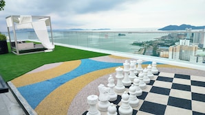 A chessboard on a rooftop with a view of a bridge and cityscape.