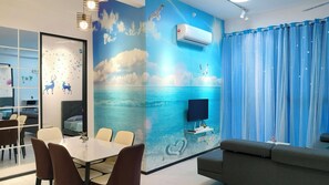 Ein Zimmer mit Wandgemälde von Meerlandschaft, einem Flachbildfernseher, einem Deckenventilator und einem Essbereich mit Stühlen und Tisch.