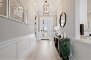 A hallway with a white door, a mirror, a lamp, and a plant. - Edenfield Championship View Estate (Sumterville)