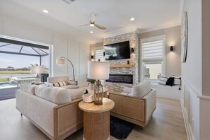A modern living room with a fireplace, comfortable seating, and a large TV. - Edenfield Championship View Estate (Sumterville)