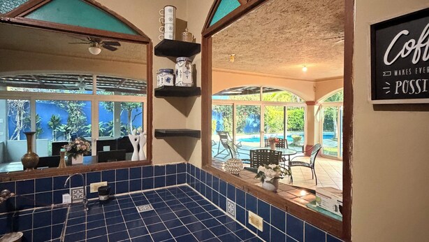 Una cucina con piastrelle blu, un cartello con la scritta 'caffè' e vista sull'esterno.