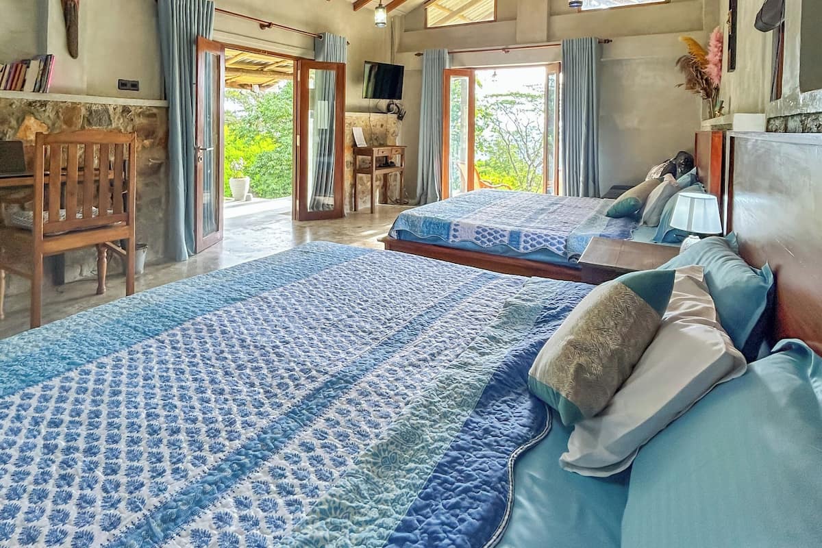 A spacious bedroom with a large bed, a wooden ceiling, and a television.