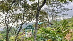 A rustic house with a green roof, surrounded by lush greenery and trees. - Unseen Knuckles Eco Boutique  (Tawalanthanna)