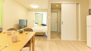A hotel room with a bed, a TV, a dining table with chairs, and a door leading to another room. - Ars Kiyosumi shirakawa (Tokyo)
