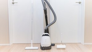 A vacuum cleaner in a room with wooden flooring, a door, and a wall. - Ars Kiyosumi shirakawa (Tokyo)