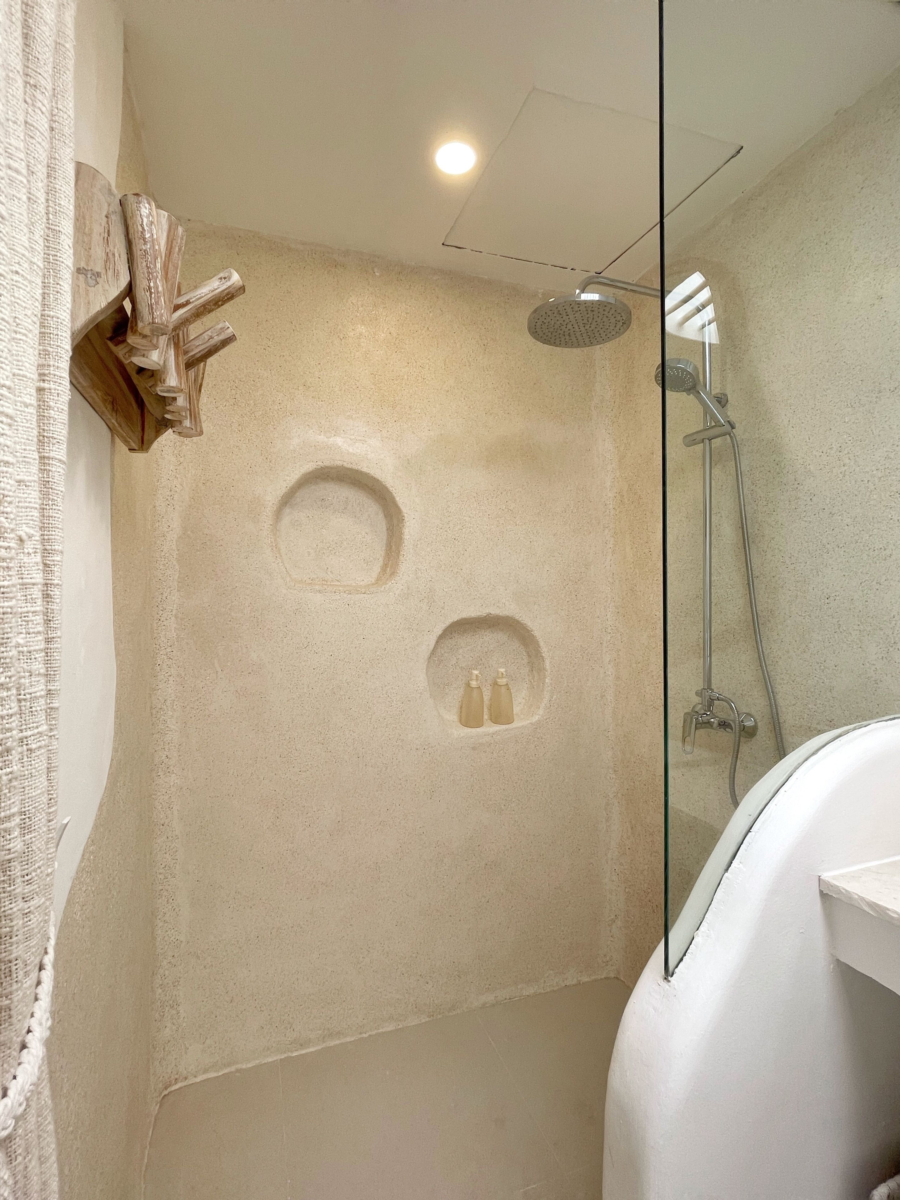 Ein modernes Badezimmer mit einer gläsernen Dusche, einem hölzernen Kreuz und einem Handtuchhalter.