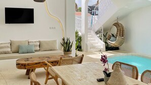 A modern interior with a pool, wicker furniture, and hanging plants. - Casa Nimare (Ungasan)