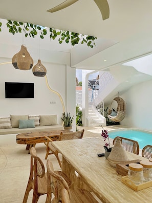 A modern interior with a pool, wicker furniture, and hanging plants. - Casa Nimare (Ungasan)