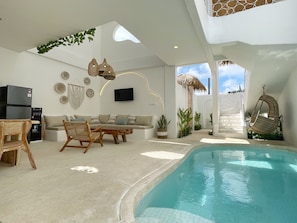 A modern living area with a pool, seating, and a TV. - Casa Nimare (Ungasan)