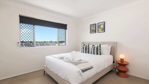 Un dormitorio con cama, ventana con vistas y una lámpara de noche.
