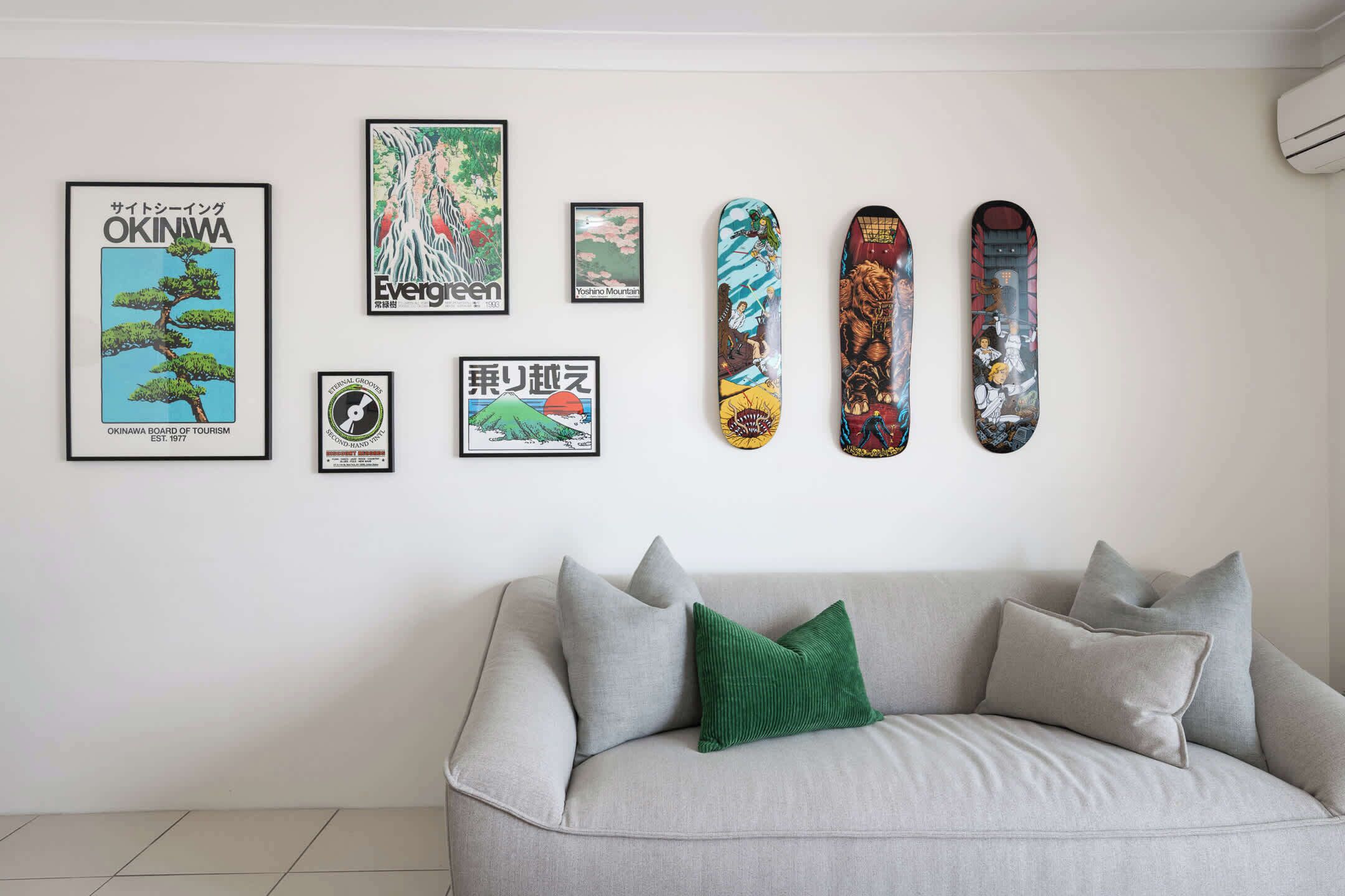 En væg med indrammede plakater og fire skateboards.