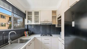Una cocina moderna con un lavaplatos de acero inoxidable, una estufa a gas y un refrigerador negro.