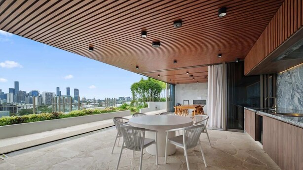 Eine moderne Dachterrasse mit Essbereich, Küche und Blick auf die Stadt.