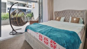 Ein Schlafzimmer mit Bett, Hängesessel und Blick auf ein Gebäude.