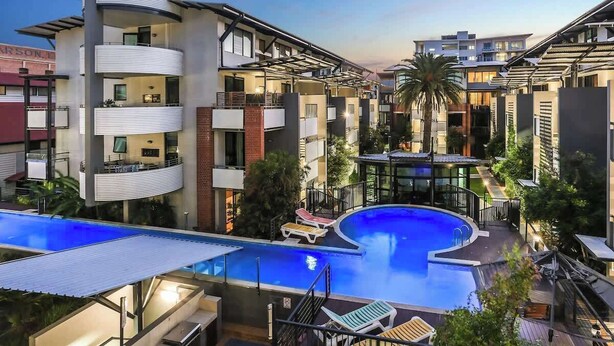 A modern hotel with a swimming pool, multiple balconies, and a rooftop terrace. - 3-Bed Teneriffe Apartment - Pool | Gym | Parking (Teneriffe)