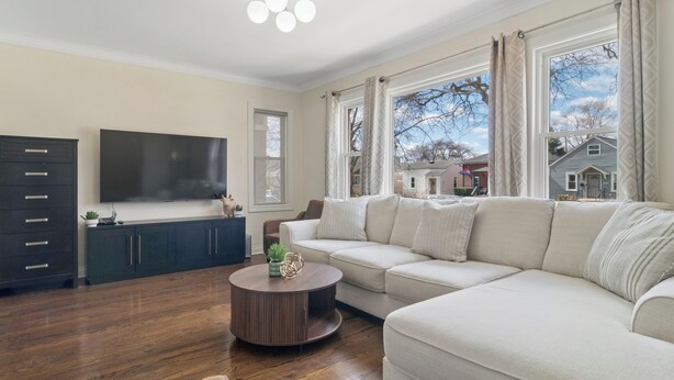 A living room with a sofa, a coffee table, a TV, and a cabinet. - Charming 5-bedroom Jefferson Park Bungalow near O’Hare (Chicago)