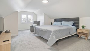 A bedroom with a bed, a nightstand, a chair, a desk, and a window. - Charming 5-bedroom Jefferson Park Bungalow near O’Hare (Chicago)