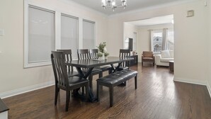 A dining room with a dark wooden table, matching chairs, and a bench. - Charming 5-bedroom Jefferson Park Bungalow near O’Hare (Chicago)