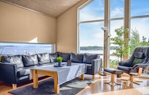 Ein modernes Wohnzimmer mit Ledersofa, Couchtisch und Sessel, mit einem großen Fenster mit Meerblick.