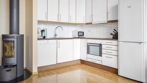 Une cuisine moderne avec des meubles blancs, une cuisinière, un four à micro-ondes et un réfrigérateur.
