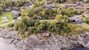 Vue aérienne d’un quartier résidentiel, avec des maisons entourées d’une forêt dense et d’un terrain rocheux.