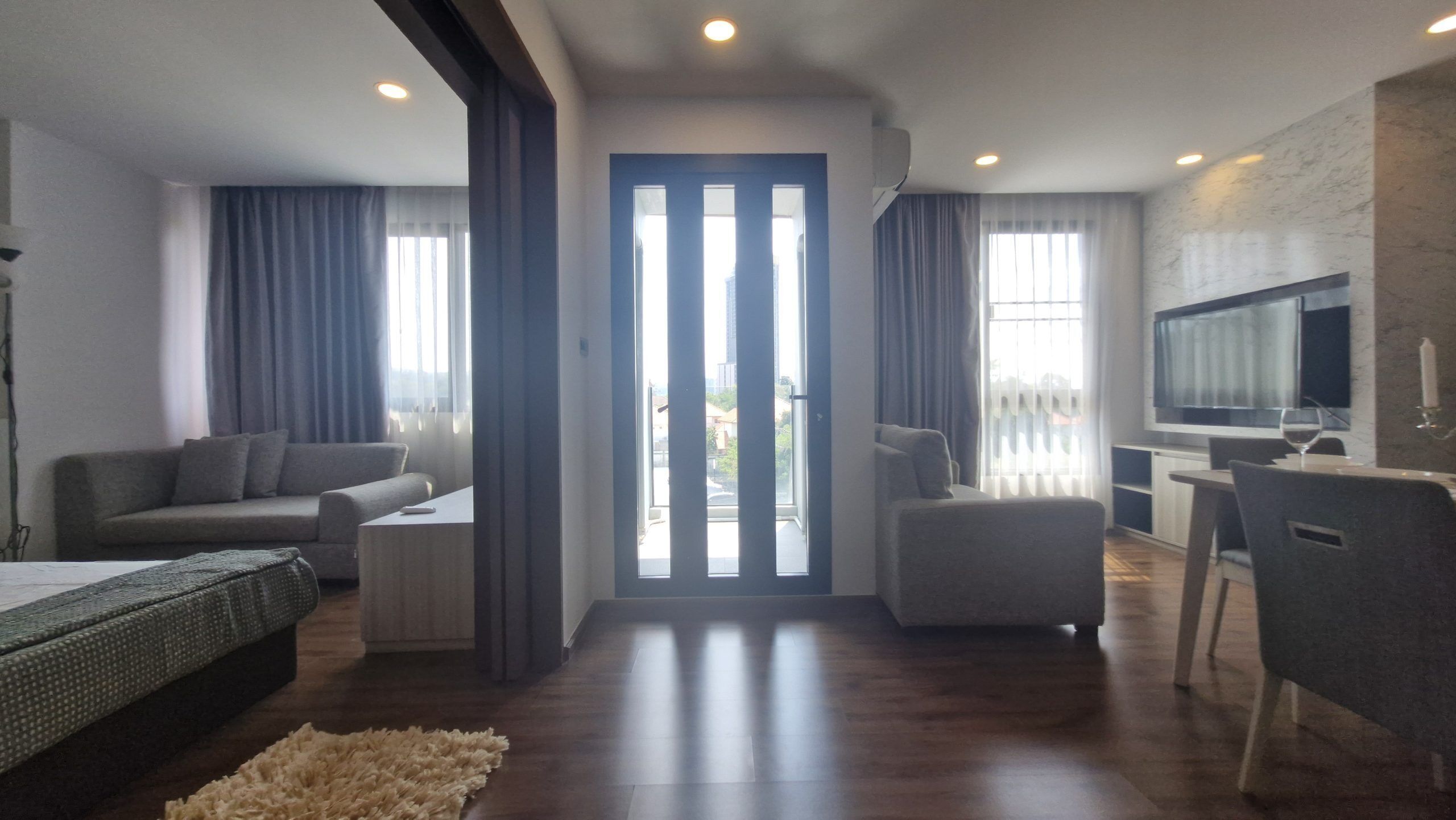 A modern living room with a sofa, a coffee table, a TV, and a dining area with a table and chairs.