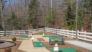 Un campo de mini golf con hoyos numerados, un banco verde y una valla blanca.