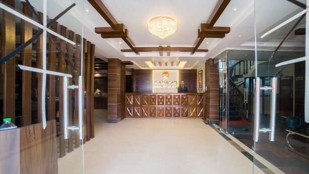 Una zona de recepción de diseño moderno, con una lámpara de araña, paneles de madera y un mostrador de recepción.