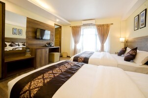 Una habitación de hotel con dos camas, televisión, escritorio y espejo.
