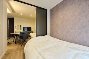Ett modernt hotellrum med en stor säng, ett skrivbord med en stol, en platt-TV och en stor spegel.