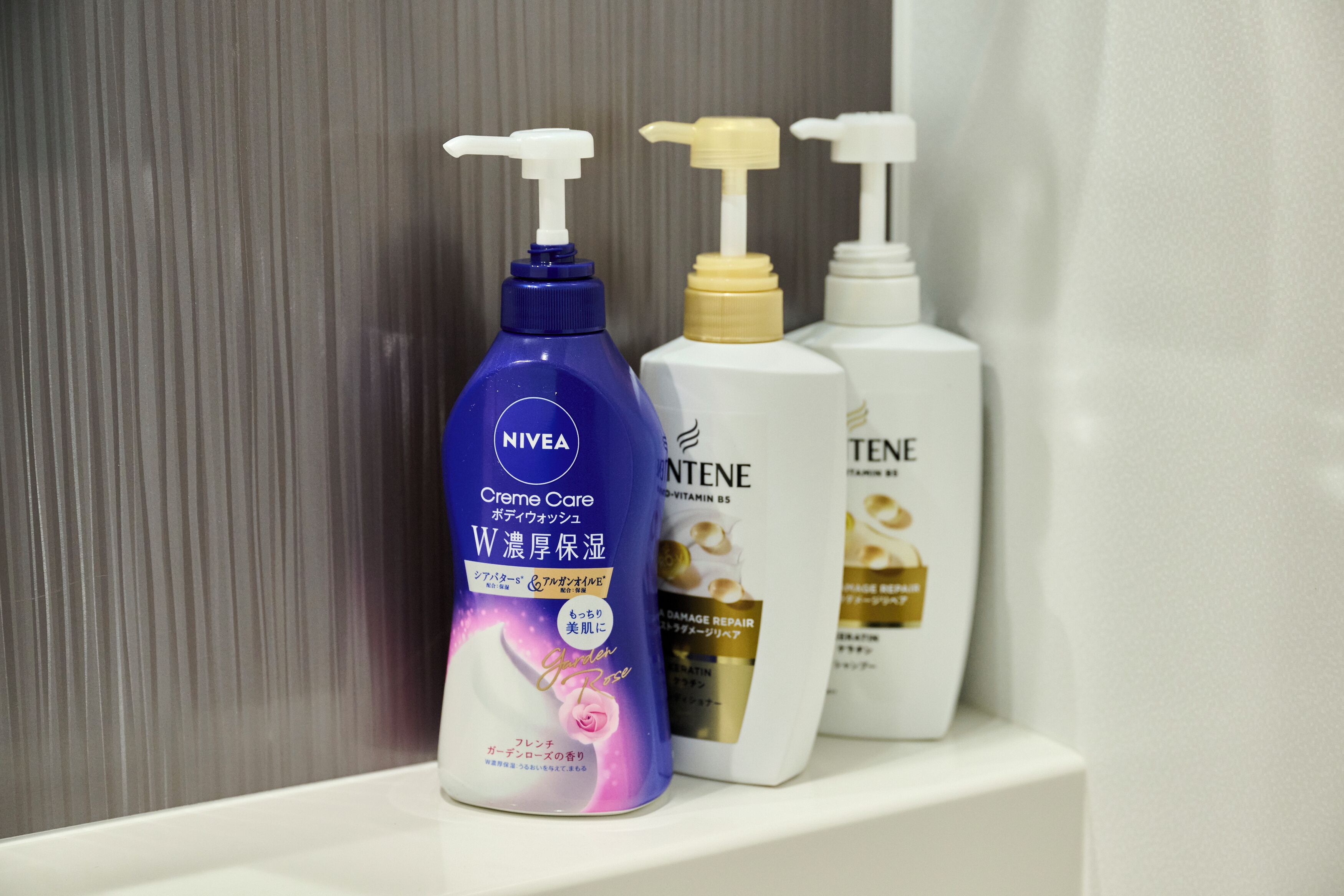 Trois flacons de produits de soins pour la peau sont posés sur une étagère.