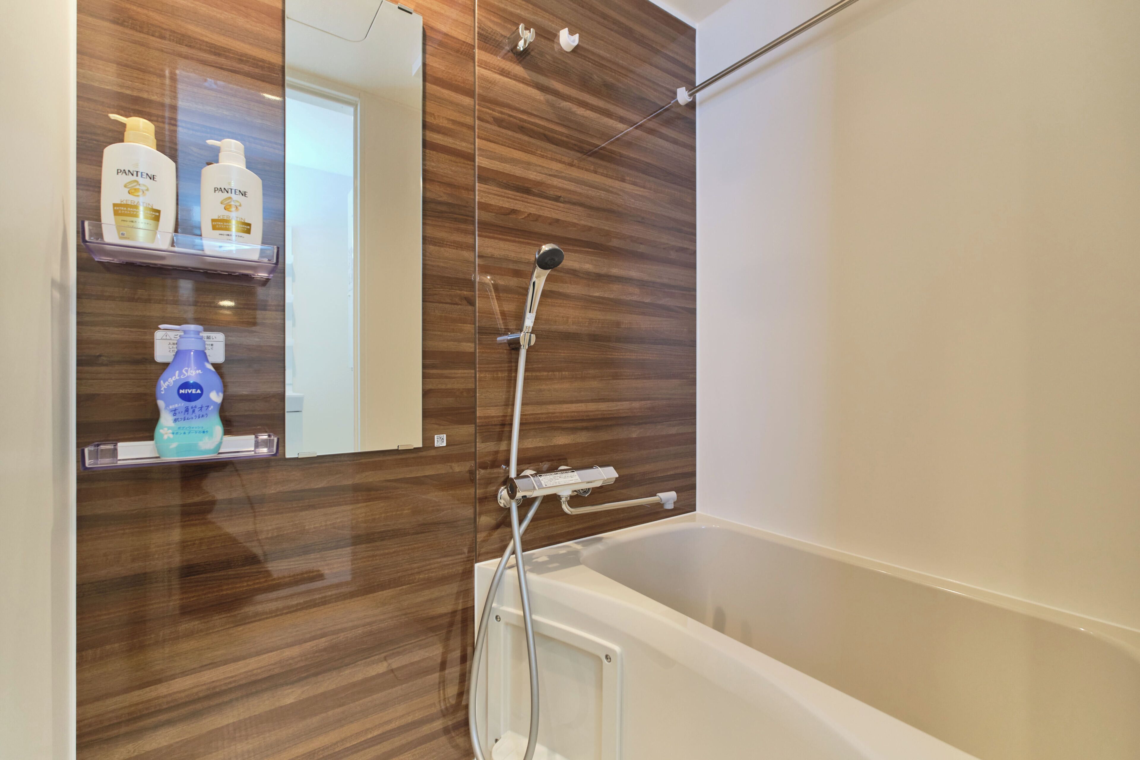 A bathroom with a wooden vanity, a mirror, and a bathtub.