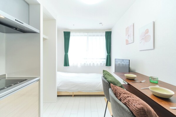 A modern room with a bed, kitchenette, dining area, and artwork on the walls.
