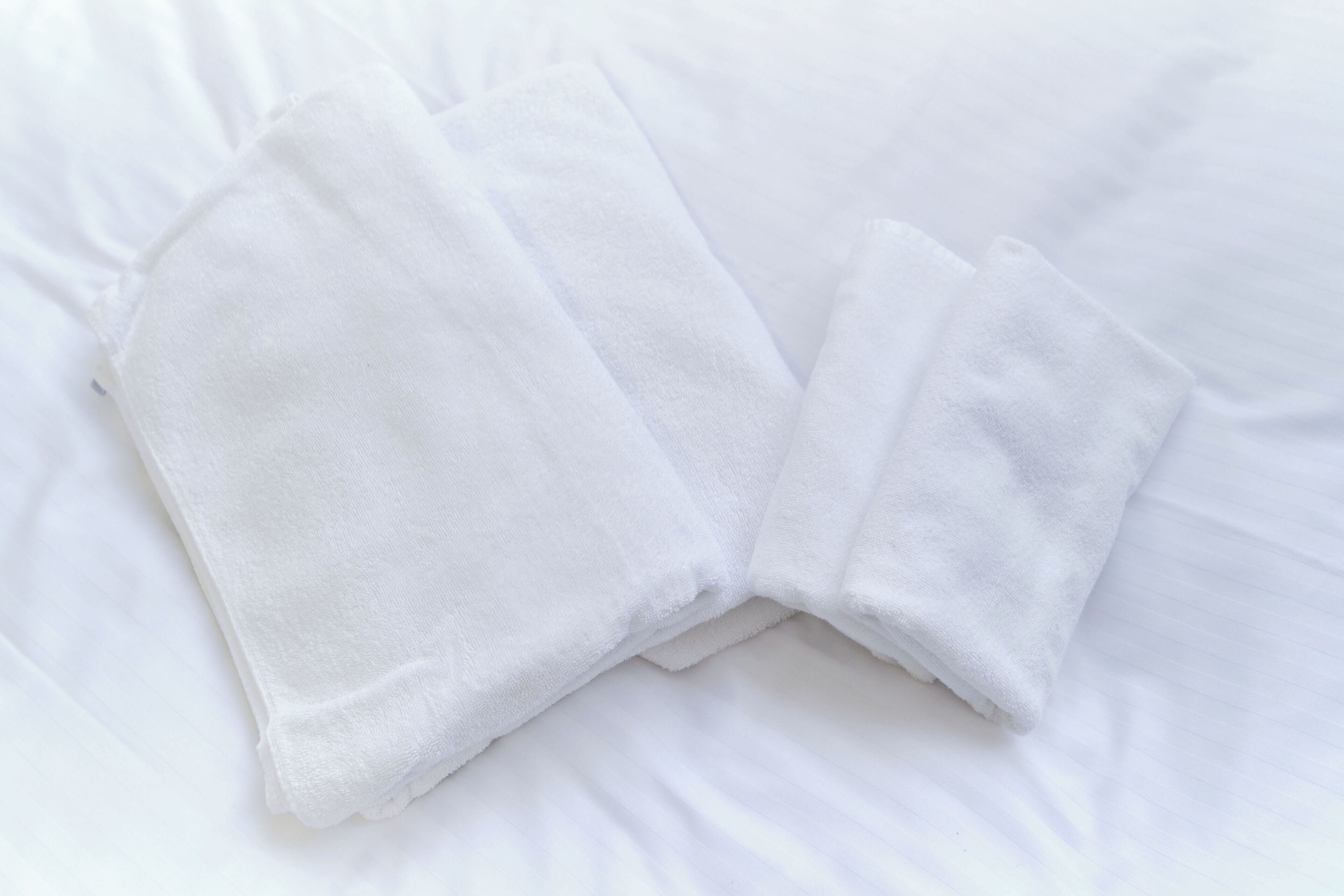 A neatly folded white towel on a bed.