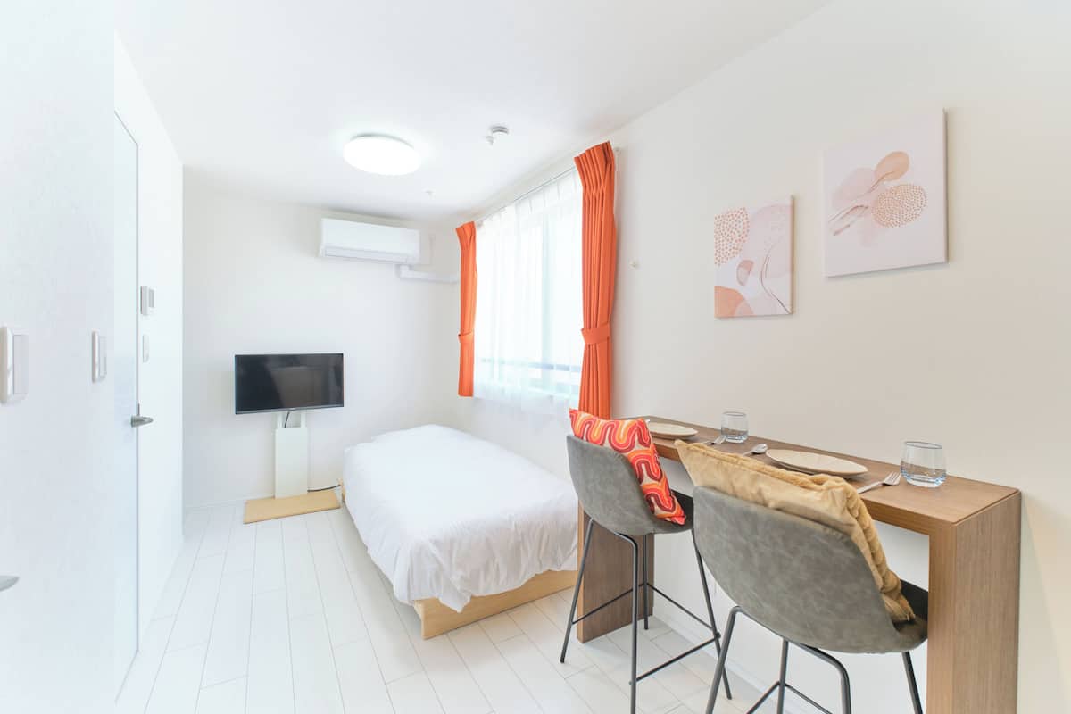 Una habitación de hotel moderna con cama, un escritorio con silla, televisión y una obra de arte en la pared.
