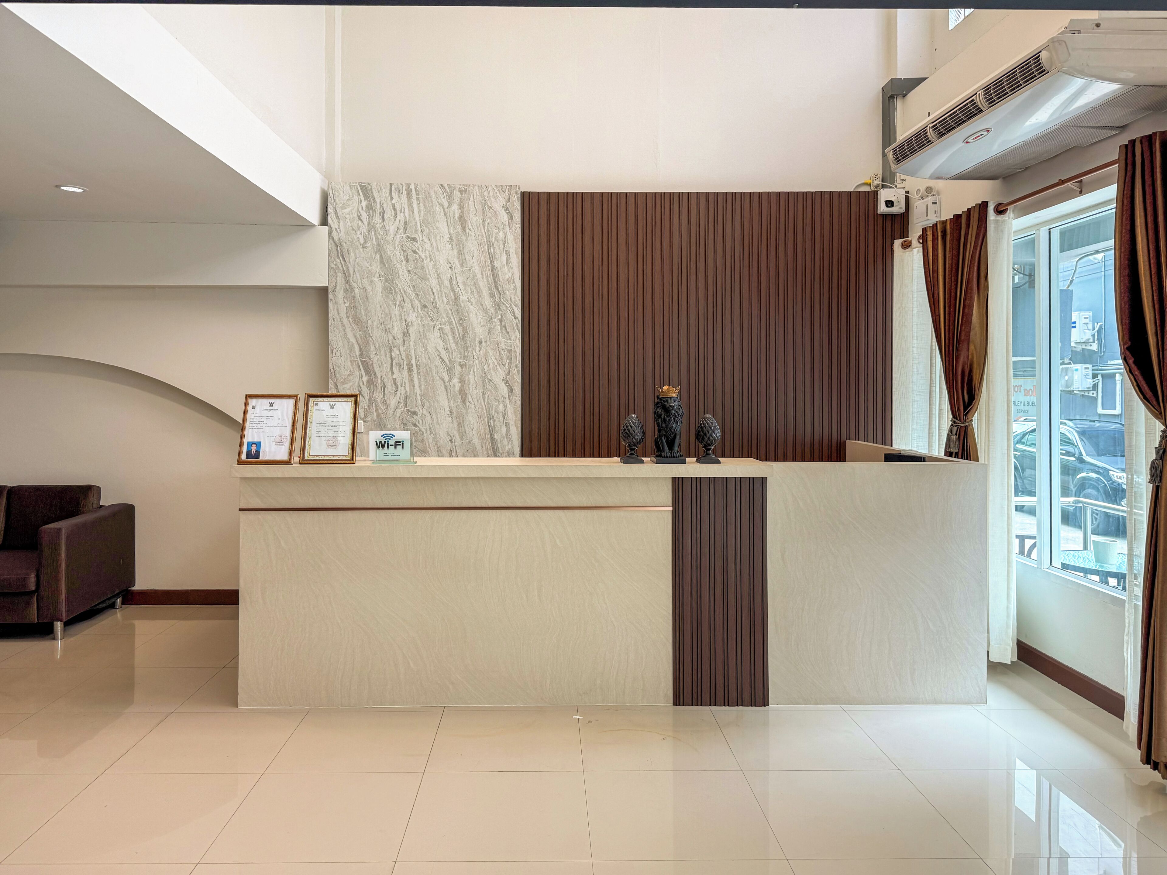 A hotel reception desk with framed certificates, a Wi-Fi sign, and decorative vases.