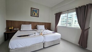 Habitación de hotel con dos camas, una mesita de noche, una ventana con cortinas y un cuadro en la pared.