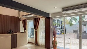 Un área de recepción de hotel con diseño moderno, un mostrador de recepción, un jarrón grande y vistas al exterior.