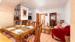 A dining area with a wooden table, chairs, and a red sofa.
