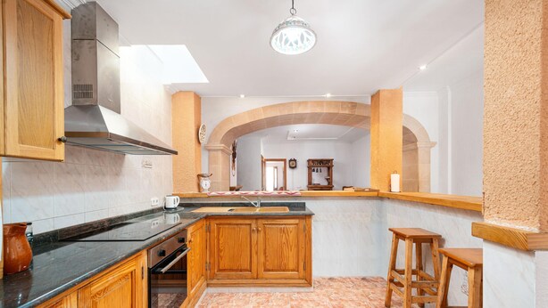 A kitchen with wooden cabinets, a built-in oven, a sink, and a tiled floor.