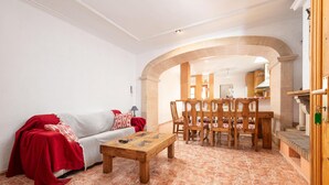 A living room with a sofa, a wooden coffee table, and a dining area with a wooden table and chairs.