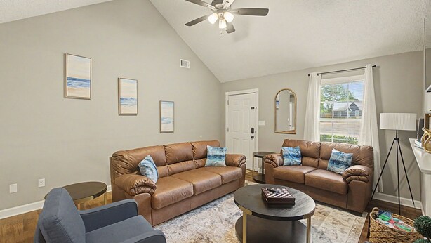 A living room with two brown leather sofas, a round coffee table, and a ceiling fan. - The Delta Dream Cottage- minutes from Memphis (Horn Lake)
