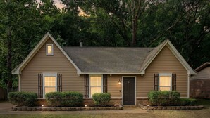 A two-story house with a front porch, a chimney, and a well-maintained lawn. - The Delta Dream Cottage- minutes from Memphis (Horn Lake)