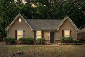 A two-story house with a front porch, a chimney, and a well-maintained lawn. - The Delta Dream Cottage- minutes from Memphis (Horn Lake)