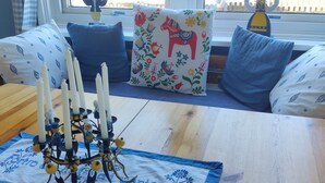 Ein Zimmer mit einem Holztisch, einem dekorativen Kerzenständer und einem Fenster mit Blick auf Bäume und einen Zaun.