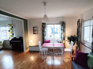 A dining area with a table and chairs, a piano, a window with curtains, and a plant. - Buntes Schwedenhaus Lillebror by Interhome (Fågelfors)