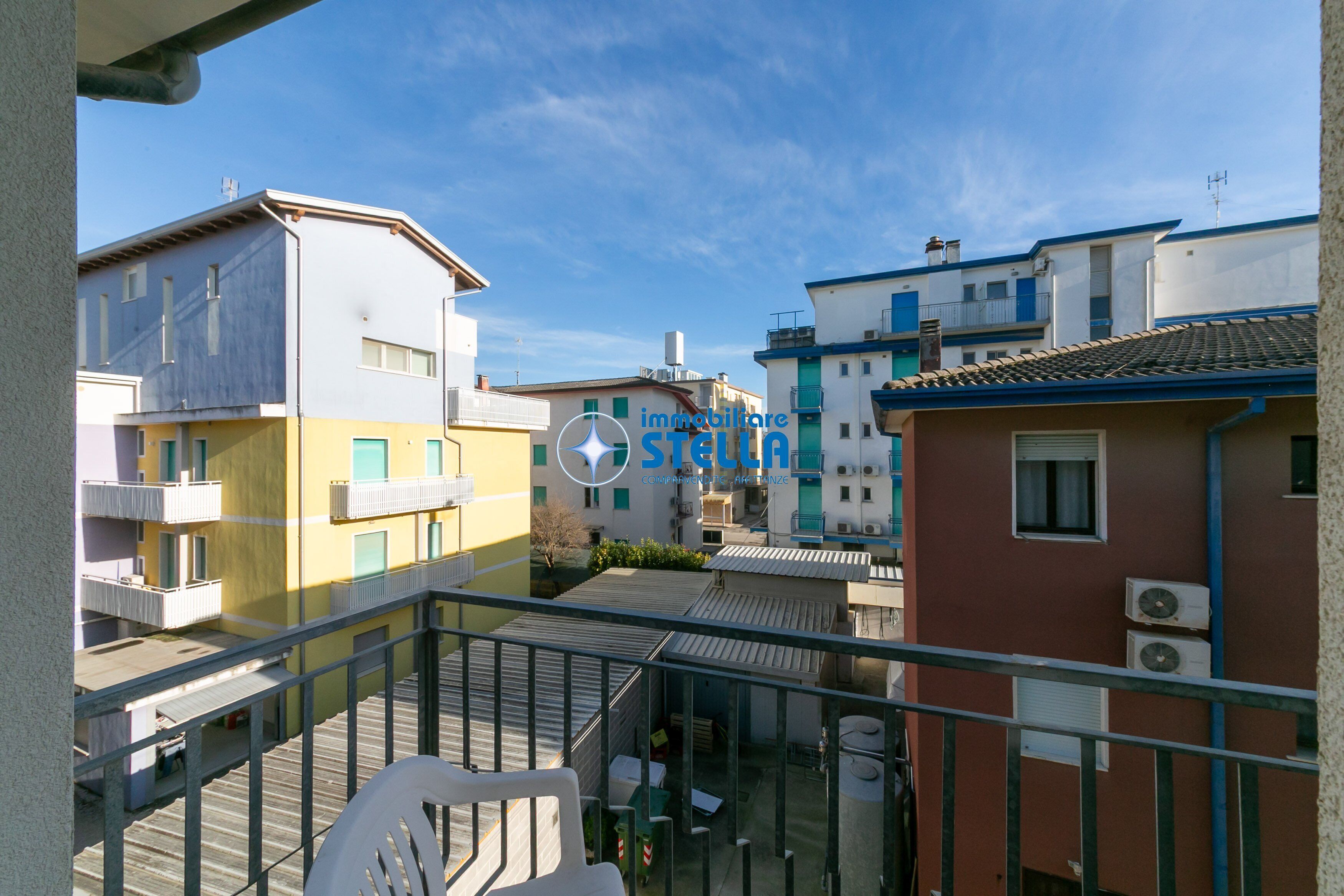 Un immeuble résidentiel doté de balcons, un ciel dégagé et le logo de « immobiliare STELLA ».