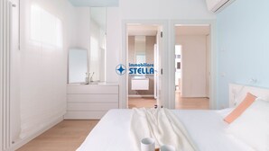 Ein modernes Schlafzimmer mit Bett, Nachttischen, einem Schminktisch und einer Klimaanlage.