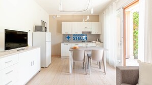 Une cuisine moderne avec un coin repas, un téléviseur à écran plat et un réfrigérateur.